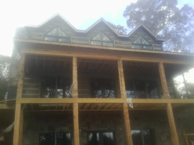Dormers and porch framing on a large log home under construction — Roof Coating work by our crew in Saint Marys