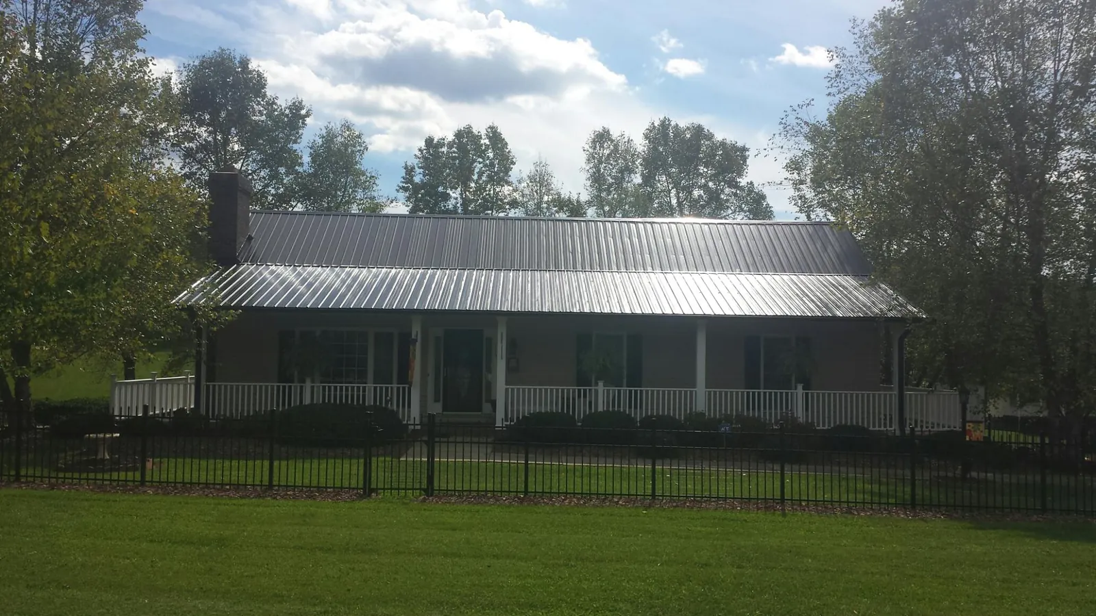 Gray metal roof on a brick ranch with a full width front porch — Gutter Guard Installation work by our crew in Saint Marys